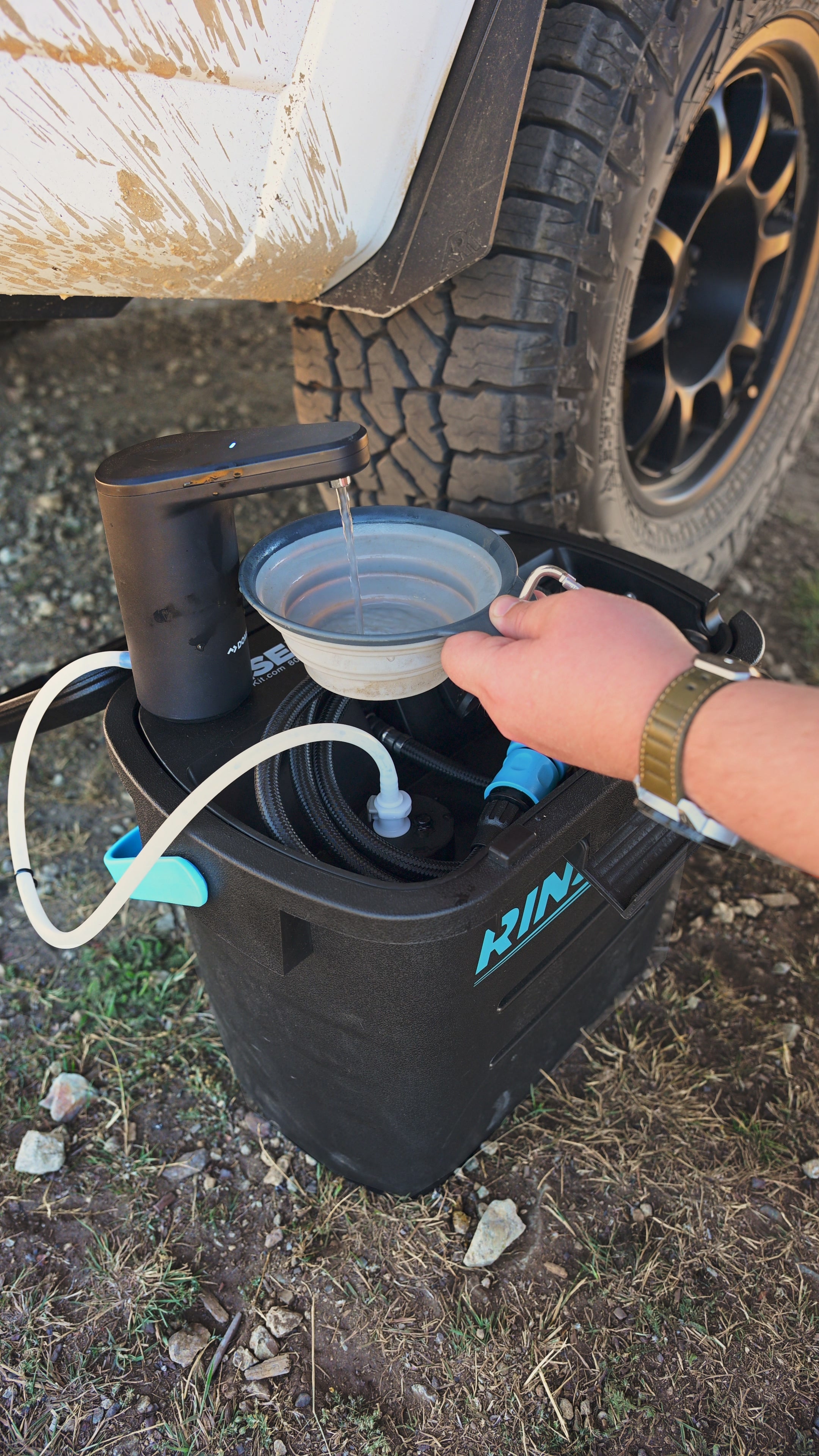 Dometic GO faucet mounted on a RinseKit Pro at camp, filling a collapsible bowl hands-free next to a truck